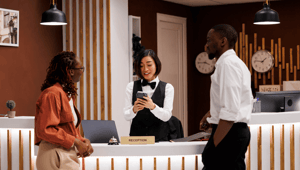 Ein Hotelangestellter und zwei Gäste unterhalten sich an der Hotelrezeption.