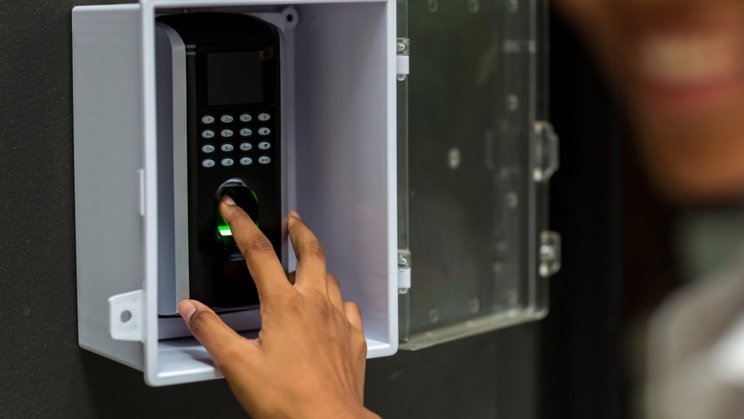 Close-up of someone putting their finger to a biometric time clock 