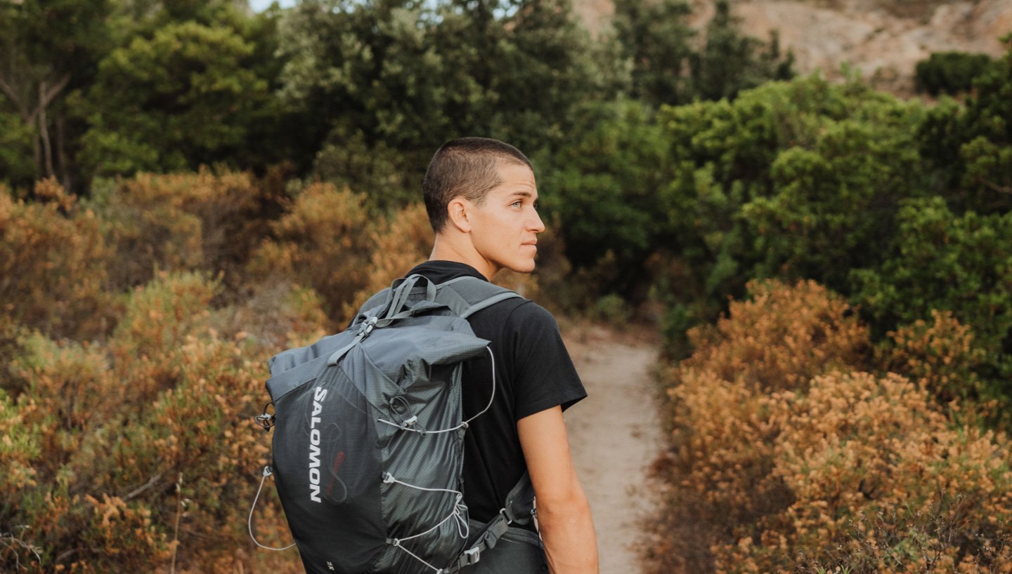 Ein Wanderer läuft durch eine bergige Landschaft mit einem Rucksack von Salomon auf dem Rücken.