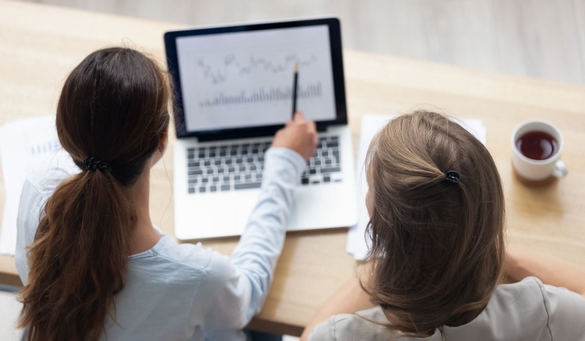 Zwei Frauen betrachten eine Grafik auf einem Laptop-Bildschirm.