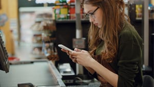 Female supermarket worker checking while sitting at the checkout