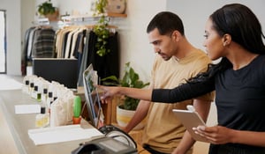 Two workers in a retail clothing store looking at a computer monitor