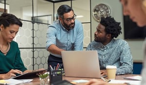 Two male members of a retail payroll team looking at a laptop together